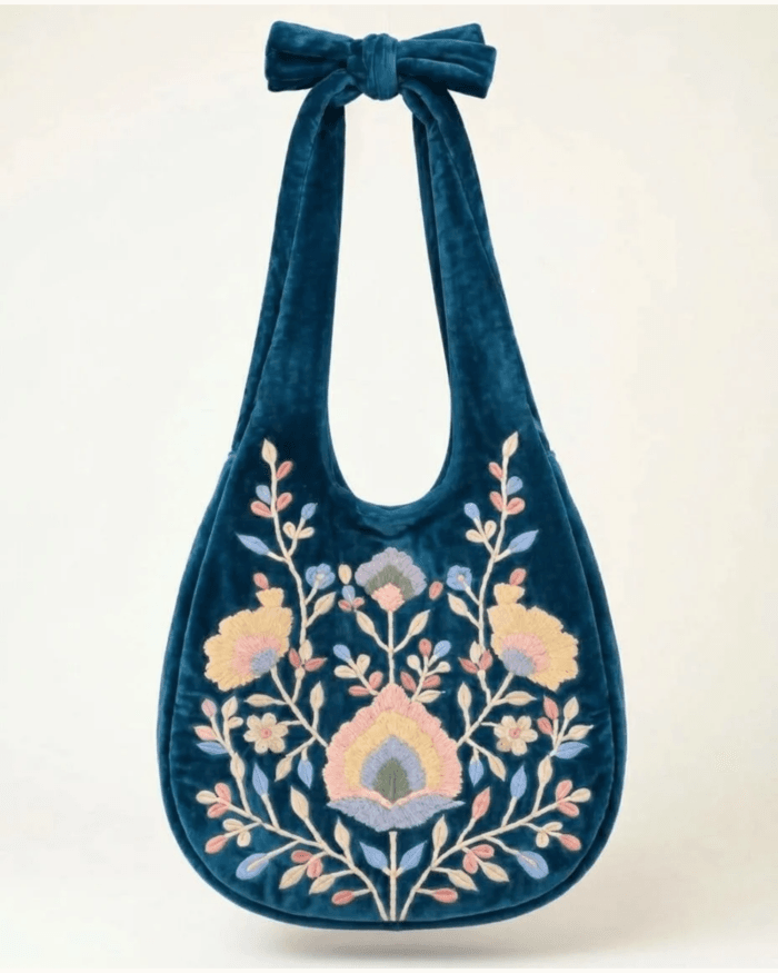 Teal velvet bag with embroidery, front view on plain background with Rodia bloom